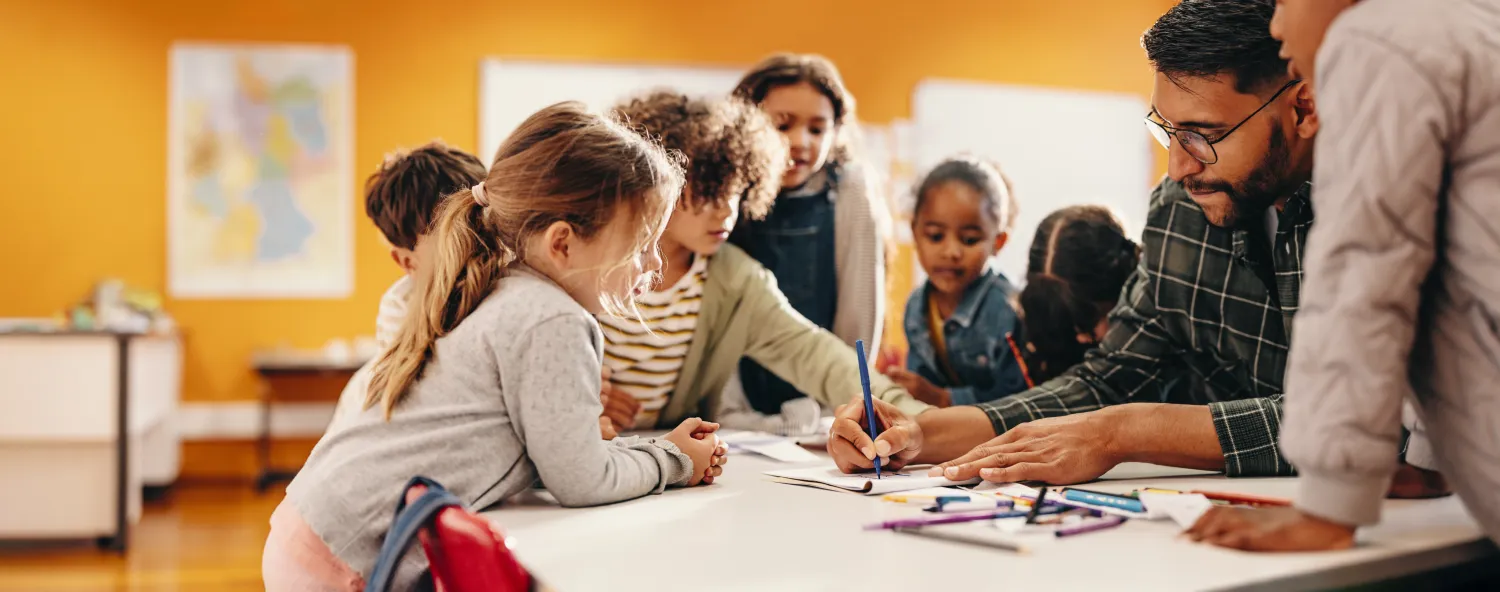 A teacher helping a group of students at a table
